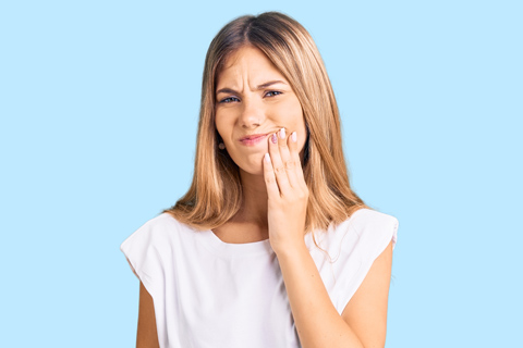 Young woman with toothache holding cheek