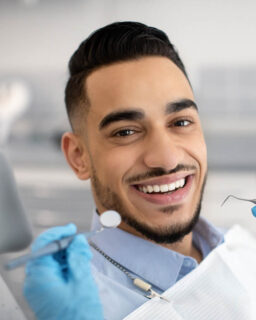 Smiling man receiving dental checkup with tools